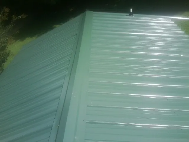 New green metal panels meeting at the ridge of a roof — Flat Roof Repair work by our crew in Apollo Beach